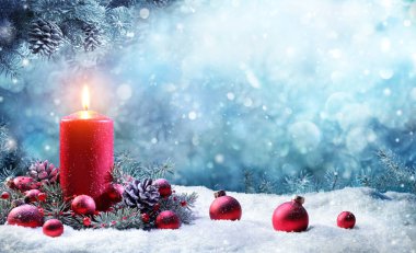 Çam dalları karlı sahnede yanan muma Advent