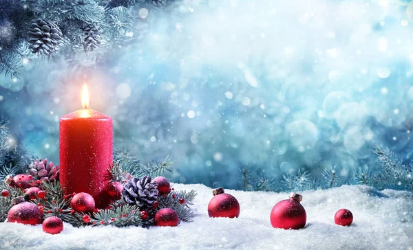Çam dalları karlı sahnede yanan muma Advent