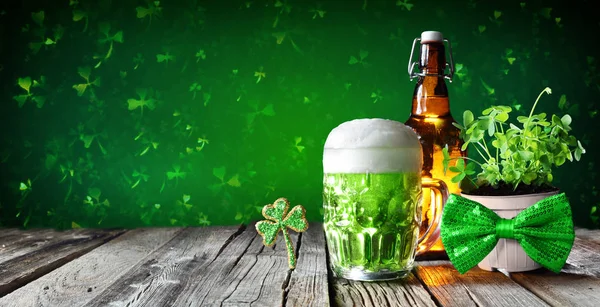 St patrick 's day - grünes Bier im Glas mit Flasche und Kleeblättern auf Holztisch — Stockfoto