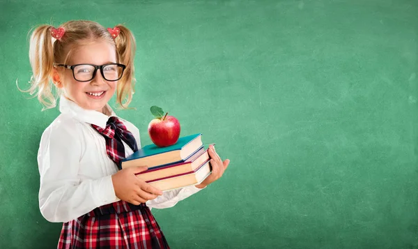 Piccola studentessa che tiene libri e mele — Foto Stock