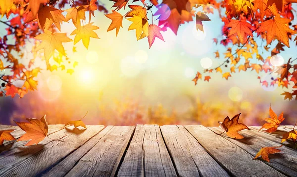 Dřevěný stůl s oranžové listy a rozostřeného pozadí podzim — Stock fotografie