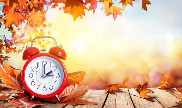 Daylight Savings tijd Concept - klok en bladeren op houten tafel — Stockfoto