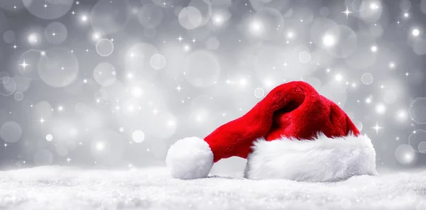 Chapéu de Papai Noel na neve e prata fundo brilhante — Fotografia de Stock