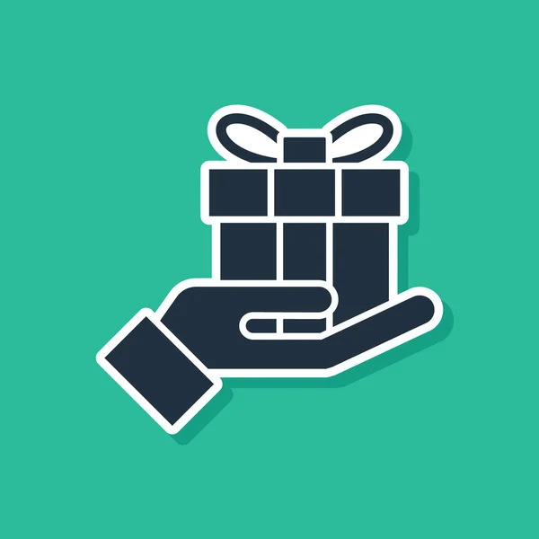 Scatola regalo blu nell'icona della mano isolata su sfondo verde. Buon Natale e felice anno nuovo. Illustrazione vettoriale — Vettoriale Stock