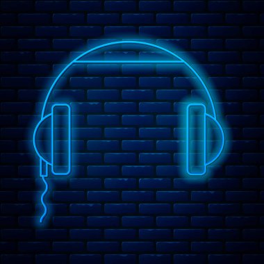 Glowing neon line Headphones icon isolated on brick wall background. Earphones sign. Concept for listening to music, service, communication and operator. Vector Illustration