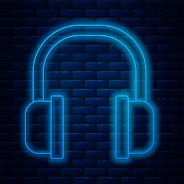 Glowing neon line Headphones icon isolated on brick wall background. Earphones sign. Concept for listening to music, service, communication and operator. Vector Illustration