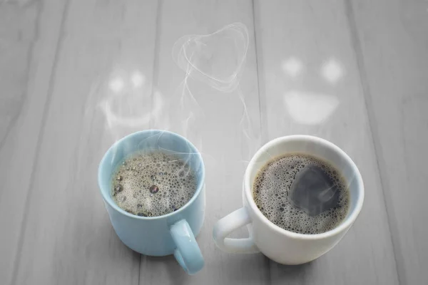 两个热咖啡和蒸汽笑脸在木桌上 — 图库照片