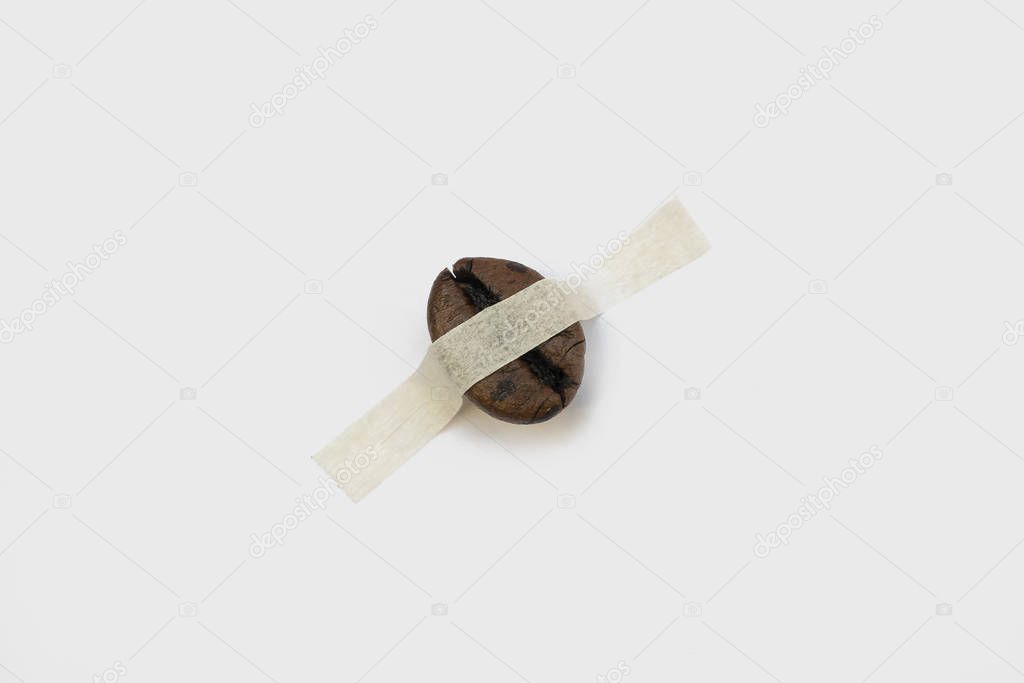 concept one coffee bean on and sticky tape white background