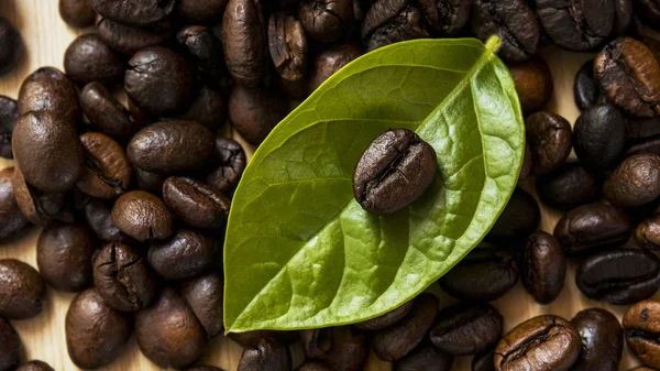 Chicchi di caffè primo piano e foglie sul tavolo di legno . — Foto Stock