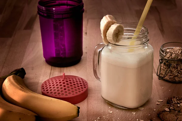 Muz, yulaf ezmesi ve yulaflı kurabiyeli içecek bardağında protein içeceği.