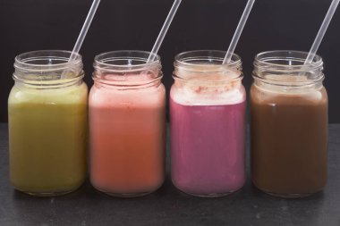 Sütlü protein karışımının farklı çeşitleri. Muzlu çilekli böğürtlen kahvesi. İçme kabında.