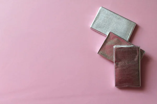 Chocolates envueltos en lámina de plata aislada sobre superficie rosa —  Fotos de Stock