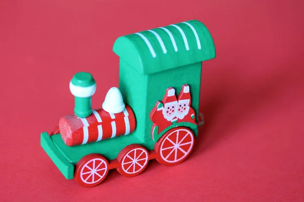 Зеленый праздничный деревянный поезд локомотив или железнодорожный двигатель на красном фоне — стоковое фото