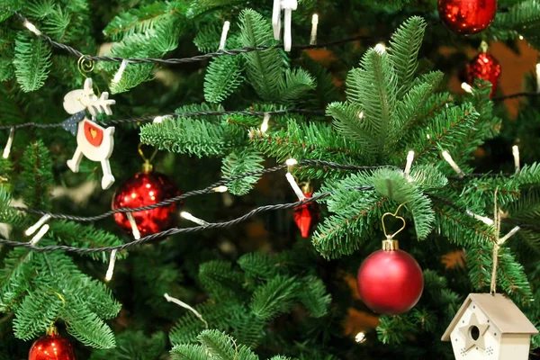 Árvore de Natal decorada com bugigangas brilhantes vermelhas e figuras de madeira — Fotografia de Stock