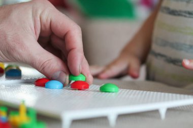 Çocuk tahta mantar çivi mozaiğiyle oynuyor