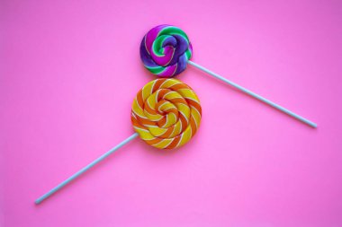 Pembe arka planda iki parlak girdap lolipop, sekiz numara şeklinde. 8 Mart için Uluslararası Kadınlar Günü tebrik kartı. Renkli ve çarpık şekerlerle dolu bir arka plan. Gökkuşağı yuvarlak tatlılar