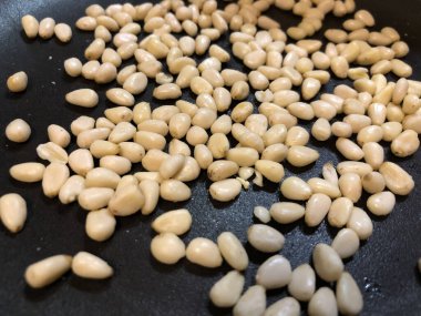 Siyah tavada kavrulmuş çam fıstığı. Sedir çekirdekleri pişirme işlemi. Yemek tarifi. Kızarmış gıda arka planı