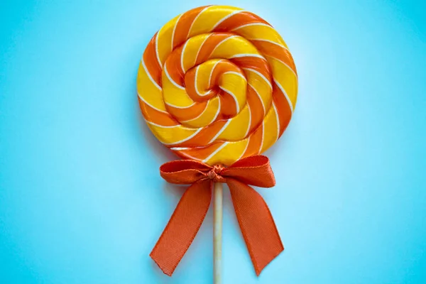 Pembe arka planda parlak kıvrımlı lolipop. Renkli bükülmüş şekerlerle şenlikli bir arka plan. Gökkuşağının etrafını sarın, tatlı çubuklar. Turuncu ve sarı kurdeleli şekerlemeler. Asgari tasarım