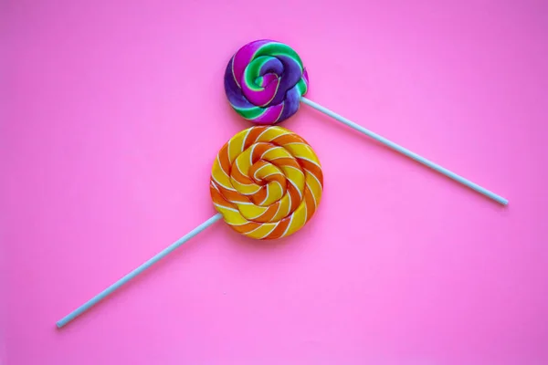 Two bright swirl lollipops on pink background in the shape of number eight. International women's day greeting card for 8 March. Festive background with colorful twisted candies. Rainbow round sweets