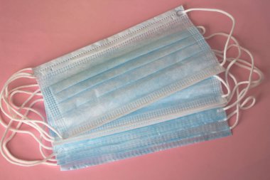 Pembe arka planda tıbbi maskeler. Salgın hastalık tüm dünyaya yayılıyor. Hastalıklı insanlar için tıbbi tedavi. Sağlık Hizmetleri