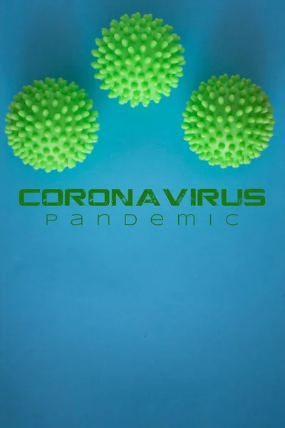 Close up of three green spiky coronavirus models isolated on blue background. Pandemic desease spreading worldwide. Medical treatment of the infected people. Healthcare