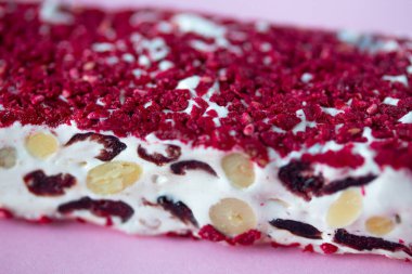Torrone ya da fındıklı ve kırmızı kuru meyveli nougat bar. Geleneksel İtalyan tatlıları pembe arka planda kapanıyor. Tatlı ve sağlıklı yiyecekler.