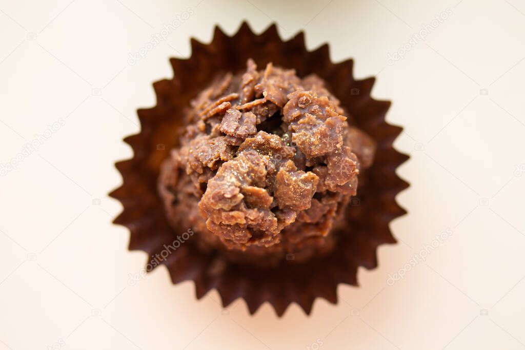 Chocolate corn flake cake in brown paper cupcake case. Close up of sweet dessert with gold dust sprinkles. Simple party cake recipe for children