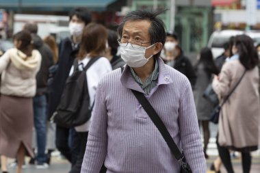 Tokyo, Japonya, 22 Şubat 2020 - Bulaşıcı hastalıkları önlemek için cerrahi maske takan bir adam Shibuya 'nın ünlü geçidinde yürüyor. Japonya, ülkede koronavirüs enfeksiyonu vakalarını doğruladı.