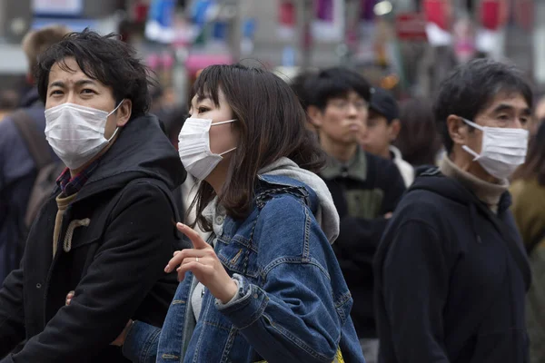 Tokyo, Japonya, 22 Şubat 2020 - Bulaşıcı hastalıkları önlemek için cerrahi maske takan yayalar Shibuya 'nın ünlü geçidinde yürüyor. Japonya, ülkede koronavirüs enfeksiyonu vakalarını doğruladı.