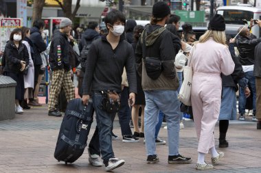 Tokyo, Japonya, 22 Şubat 2020 - Bulaşıcı hastalıkları önlemek için cerrahi maske takan bir adam Shibuya 'nın ünlü geçidinde yürüyor. Japonya, ülkede koronavirüs enfeksiyonu vakalarını doğruladı.