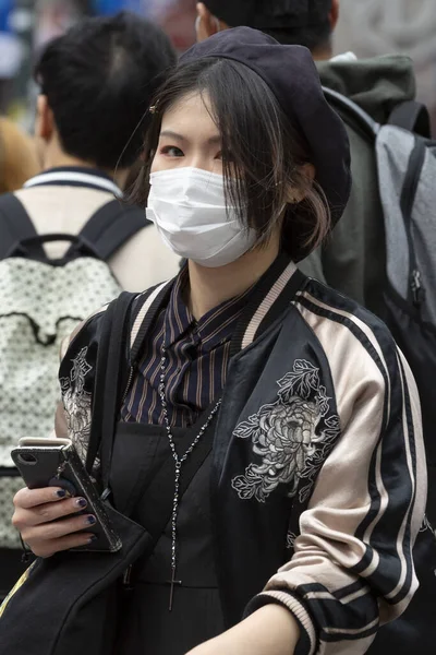 Tokyo, Japonya, 22 Şubat 2020 - Bulaşıcı hastalıkları önlemek için cerrahi maske takan bir kadın Shibuya 'nın ünlü geçidinde yürüyor. Japonya, ülkede koronavirüs enfeksiyonu vakalarını doğruladı.