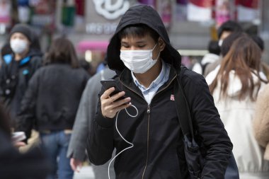 Tokyo, Japonya, 22 Şubat 2020 - Bulaşıcı hastalıkları önlemek için cerrahi maske takan bir adam Shibuya 'nın ünlü geçidinde yürüyor. Japonya, ülkede koronavirüs enfeksiyonu vakalarını doğruladı.