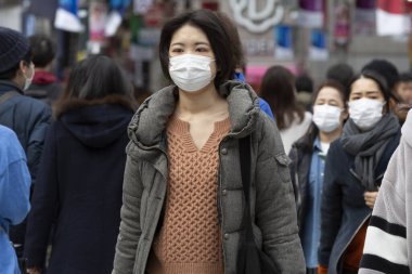 Tokyo, Japonya, 22 Şubat 2020 - Bulaşıcı hastalıkları önlemek için cerrahi maske takan bir kadın Shibuya 'nın ünlü geçidinde yürüyor. Japonya, ülkede koronavirüs enfeksiyonu vakalarını doğruladı.