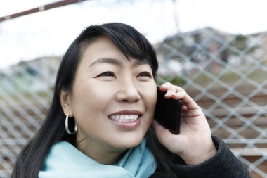 Japon kadın sokakta akıllı telefonla konuşuyor..