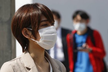 Tokyo, Japonya, 8 Nisan 2020 - Yayalar Shinjuku 'daki yeni koronavirüs salgını sırasında önleyici bir önlem olarak yüz maskesi takıyorlar.