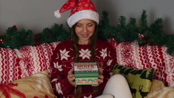 Happy Girl w Santa Claus kapelusz otwiera pudełko świąteczne z magicznym światłem wewnątrz — Wideo stockowe