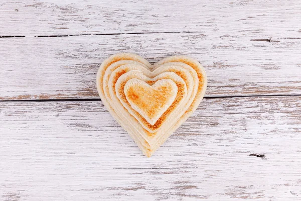 Pile of toasted bread hearts on wooden table, concept of support in big family — Stock Photo, Image