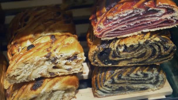Vitrine mit süßen Brötchen in einem Café. Bäckerei mit Mohn, Rosinen und Marmelade — Stockvideo