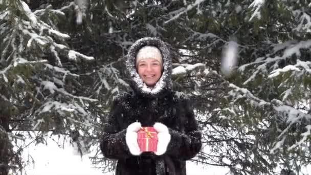 Glücklich lächelnde Frau in Winterkleidung mit roter Weihnachtsgeschenkschachtel in der Hand — Stockvideo