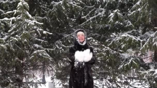 Mulher feliz se divertindo no parque de inverno brincando com neve e lança flocos de neve — Vídeo de Stock