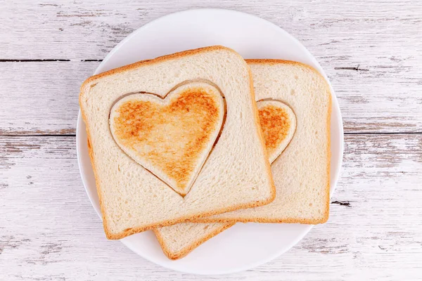 Pan tostado en rodajas corazones en mesa de madera, concepto de desayuno familiar feliz —  Fotos de Stock