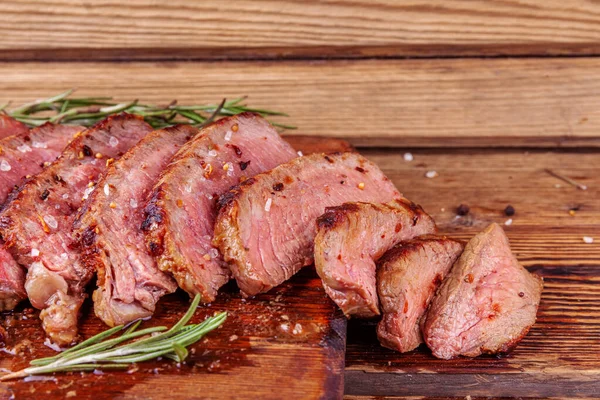 Bistecca di manzo affettata alla griglia Ribeye con spezie sul tagliere in legno rustico — Foto Stock