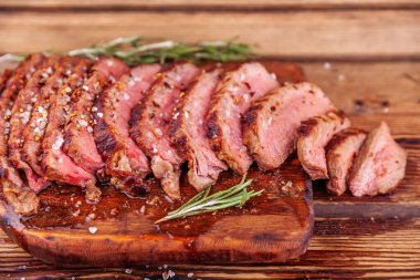 Tahta kesim tahtasında dilimlenmiş et bifteği, baharatlar ve biberiye.