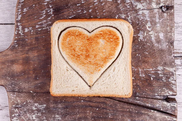 Pan tostado con el corazón cortado en la tabla de la vendimia, concepto feliz día de San Valentín —  Fotos de Stock