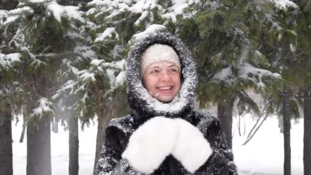 Счастливая женщина смотрит вверх и радуется снегопаду, стоящему в парке — стоковое видео