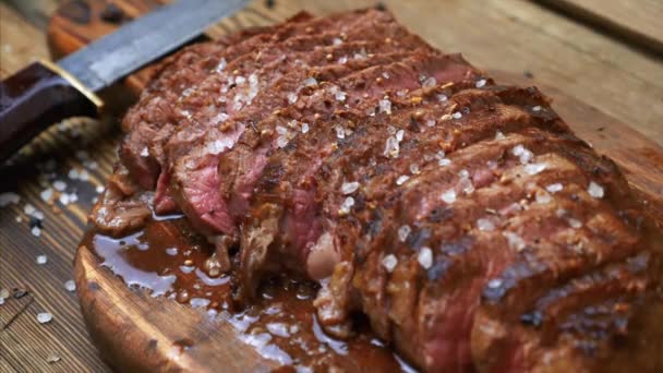 Szeletelt grillezett húsmarha steak Ribeye fűszerekkel rusztikus fa vágódeszka — Stock videók