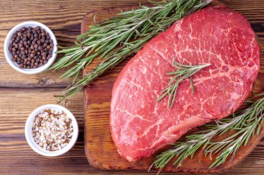 Köy ahşap tahtasında biberiye ve şifalı otlarla servis edilen çiğ taze biftek.