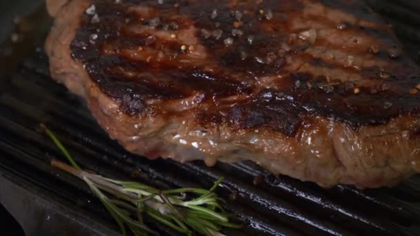 Close Up of Beef Steak Grilling on Grid with Salt and Rosemary
