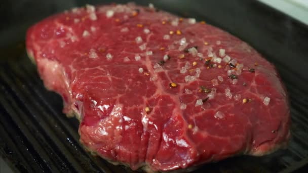 Delicioso filete de carne jugosa con sal y pimienta cocinando en la parrilla con humo — Vídeo de stock