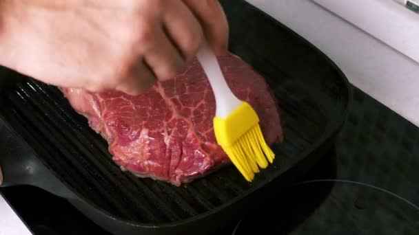 Man Hand gladstrijkende olie met een siliconen borstel op gegrilde biefstuk op grillpan — Stockvideo